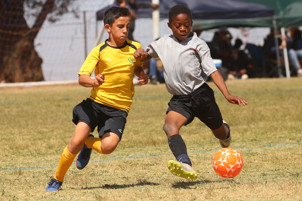 Two young boys energetically competing in a soccer match on a grassy field.